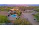 Expansive aerial view showcasing a pool, hot tub, desert landscaping, and stunning mountain views at sunset at 13627 E Monument Dr, Scottsdale, AZ 85262