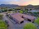 An aerial view showcasing the home's architecture, garages, and desert landscape against a mountain backdrop at 13627 E Monument Dr, Scottsdale, AZ 85262