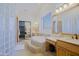 An airy main bathroom featuring a tub, vanity, and glass block window at 13627 E Monument Dr, Scottsdale, AZ 85262