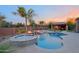 Beautiful pool and spa area with a rock waterfall feature and an outdoor kitchen and dining area at 13627 E Monument Dr, Scottsdale, AZ 85262
