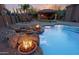 Luxury pool and spa area with rock features, fire bowls, and a covered outdoor kitchen at 13627 E Monument Dr, Scottsdale, AZ 85262