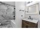 Stylish bathroom with a wood vanity, marble counters, and a shower-tub combo with gray-toned tiles at 1533 W Culver St, Phoenix, AZ 85007