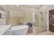 Bright bathroom featuring a soaking tub, glass shower with bench, and walk-in closet at 16044 S 24Th Pl, Phoenix, AZ 85048