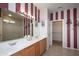 Bathroom featuring a double vanity, tiled floor, large mirror, and glass shower door at 19212 N Tallowood Way, Surprise, AZ 85387