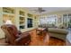 Comfortable living room featuring hardwood floors, custom built-ins, and large windows with plantation shutters at 19212 N Tallowood Way, Surprise, AZ 85387