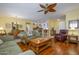 Open-concept living room with wood floors, a ceiling fan, and direct access to the dining room and kitchen at 19212 N Tallowood Way, Surprise, AZ 85387