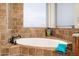 Luxurious bathroom features a soaking tub with tile surround and bright natural light at 22043 N 59Th Dr, Glendale, AZ 85310