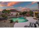 Twilight view of a private backyard pool with waterfall feature and desert landscaping against a beautiful, colorful sky at 22043 N 59Th Dr, Glendale, AZ 85310