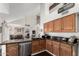 Bright kitchen featuring wooden cabinetry, black countertops, stainless steel dishwasher, and a view of the living room at 2218 E Mallard Ct, Gilbert, AZ 85234