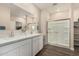 Well-lit bathroom featuring dual sinks, wood-look flooring, and a glass-enclosed walk-in shower at 2475 W Spaulding Ave, Apache Junction, AZ 85120