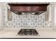 Close up of the black gas range and decorative backsplash in this modern kitchen at 28834 N 68Th Ave, Peoria, AZ 85383
