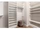 Organized walk-in closet with white shelving units, wood floors, and a comfortable pouf at 28834 N 68Th Ave, Peoria, AZ 85383