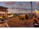 Inviting backyard featuring a hot tub, an outdoor kitchen, mature landscaping, and a colorful sunset at 29794 N Little Leaf Dr, San Tan Valley, AZ 85143