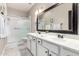 Well-lit bathroom featuring a double sink vanity, framed mirror, and walk-in shower with glass door at 29794 N Little Leaf Dr, San Tan Valley, AZ 85143