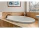 Close-up of bathroom with a large bathtub surrounded by travertine tile at 3353 E Nolan Dr, Chandler, AZ 85249