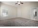 Carpeted bedroom features a modern ceiling fan, bright windows, and neutral colored walls at 3847 W Yellow Peak Dr, San Tan Valley, AZ 85144