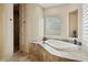 A luxurious soaking tub and tiled shower featuring travertine tile and natural light from three windows at 40627 N 6Th Ave, Phoenix, AZ 85086