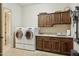 Laundry room with front-load washer and dryer, wooden cabinets, and tile floor at 40627 N 6Th Ave, Phoenix, AZ 85086