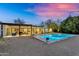 Lovely backyard showcasing a sparkling pool, a cozy patio, and a contemporary home at twilight at 5033 E Turquoise Ave, Paradise Valley, AZ 85253