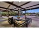 Evening view of the covered outdoor living area featuring comfortable seating, a ceiling fan, and a view of the pool at 5033 E Turquoise Ave, Paradise Valley, AZ 85253