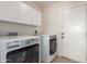 Bright laundry area with modern washer and dryer, ample storage cabinets, and exterior door access at 547 E Sack Dr, Phoenix, AZ 85024