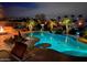 Backyard at dusk featuring a pool with rock waterfall and ambient lighting illuminating the desert landscape at 560 W Powell Way, Chandler, AZ 85248