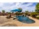 Backyard showcases a pool with rock waterfall and an island with umbrella set amongst desert landscaping at 560 W Powell Way, Chandler, AZ 85248