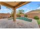 The covered patio is adjacent to the pool, featuring a tiled waterfall and surrounded by lush landscaping and a block fence at 696 W Glen Canyon Dr, San Tan Valley, AZ 85140