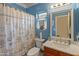 Bright blue bathroom with a decorative shower curtain and white framed mirror at 760 W Douglas Ave, Gilbert, AZ 85233
