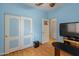 Bedroom with blue walls, wood-look floors, wall-mounted TV, closet, and ceiling fan at 760 W Douglas Ave, Gilbert, AZ 85233