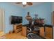 Bedroom with blue walls, wood-look floors, a desk, wall-mounted TV, and ceiling fan at 760 W Douglas Ave, Gilbert, AZ 85233