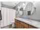 Stylish bathroom with wood cabinets, granite countertop, round mirrors, and shower with grey and white patterned tile at 8014 W Ross Ave, Peoria, AZ 85382