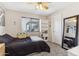 Comfortable bedroom with window light, ceiling fan, carpet flooring, large mirror and bright white bookshelf at 8014 W Ross Ave, Peoria, AZ 85382