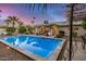 Inviting backyard pool with modern patio, grill, outdoor seating, and lush landscaping in the evening at 8738 E Rose Ln, Scottsdale, AZ 85250
