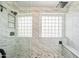 Walk-in shower featuring glass block windows, a bench, and marble-style walls at 9364 S Margo Dr, Tempe, AZ 85284