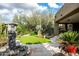 Beautiful backyard featuring artificial turf, a stone water feature, and a variety of desert plants and cacti at 9722 E Mark Ln, Scottsdale, AZ 85262