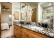 Bathroom featuring dual sinks with granite countertops and light wood cabinetry at 9722 E Mark Ln, Scottsdale, AZ 85262