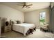 Bright bedroom with a queen-size bed, carpet, wooden ceiling fan, and a large window offering garden views at 9722 E Mark Ln, Scottsdale, AZ 85262