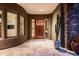 A modern desert home entrance featuring a sleek door, stone accents, and travertine flooring at 9722 E Mark Ln, Scottsdale, AZ 85262