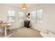Bright bedroom features neutral carpeting, dual windows, desk, and stylish lighting fixture at 12351 W Palmaire Ave, Glendale, AZ 85307