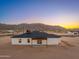 The back exterior features a minimalist covered patio and picture windows with sunset desert mountain views at 16567 N Slate Ln, Maricopa, AZ 85139