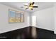 Bright, empty bedroom with a dark wood floor, white walls, ceiling fan, and bright window with plantation shutters at 17025 E La Montana Dr # 123, Fountain Hills, AZ 85268