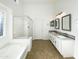 Bright bathroom featuring a dual sink vanity, soaking tub, and a glass enclosed shower at 17494 N Maddaloni Ave, Maricopa, AZ 85138
