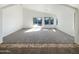 Bright living room offers plush carpeting and sliding glass doors to a well-maintained backyard at 17494 N Maddaloni Ave, Maricopa, AZ 85138
