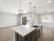 Open-concept kitchen with an island, quartz countertops, pendant lighting, and stainless sink at 17621 W Pierson St, Goodyear, AZ 85395