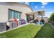 Well-maintained backyard with artificial turf, covered patio, bar stools, and a barbecue, ideal for outdoor entertaining at 21387 W Meadowbrook Ave, Buckeye, AZ 85396