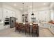A bright kitchen boasts white cabinetry, a stainless steel refrigerator and a large quartz island with seating at 21387 W Meadowbrook Ave, Buckeye, AZ 85396