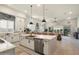 A modern kitchen showcases a stainless steel dishwasher, white cabinets and a large island open to the living room at 21387 W Meadowbrook Ave, Buckeye, AZ 85396