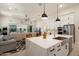A kitchen with a quartz island and stainless steel sink overlooks an open concept living room and backyard at 21387 W Meadowbrook Ave, Buckeye, AZ 85396