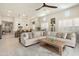 Open-concept living room with plush sofa, a stylish ceiling fan, and a seamless view into the modern kitchen at 21387 W Meadowbrook Ave, Buckeye, AZ 85396